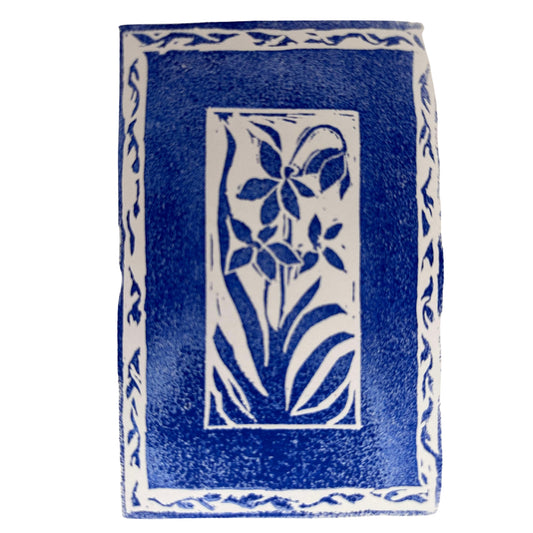 This stunning piece of Rustic County's Framed Florals Handmade Stamp Art showcases a blue and white linocut design featuring a stylized iris flower with leaves at the center. The handcrafted artwork is elegantly framed with a decorative border, highlighting its intricate patterns and striking contrasts.