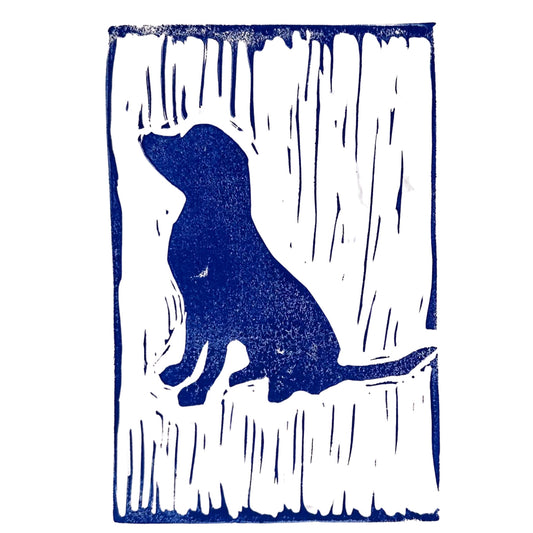 Introducing the Puppy Love Handmade Stamp Art by Rustic County: a stunning blue and white linocut-style print featuring a sitting dog in silhouette. With its textured vertical line background, this piece makes for an exceptional personalized gift and is truly a testament to handmade artistry.