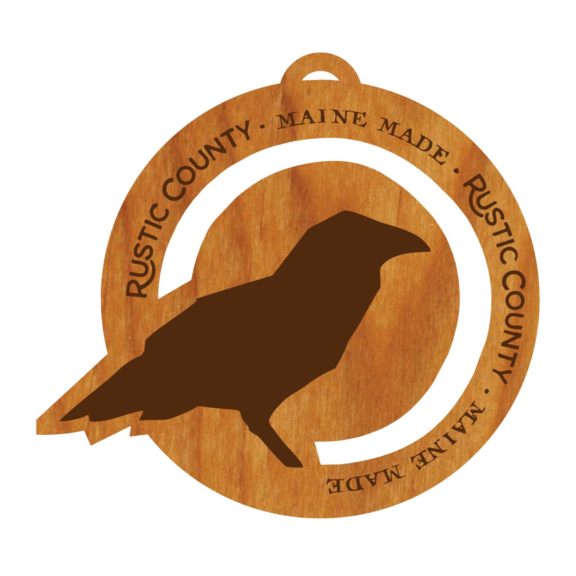 This Rustic County Crow Wood Ornament features a silhouette of a crow, skillfully carved into a wooden circle. "RUSTIC COUNTY • MAINE MADE" is engraved around the edges, adding a touch of authenticity. The piece hangs elegantly with a leather tie, making it perfect for any rustic decor.